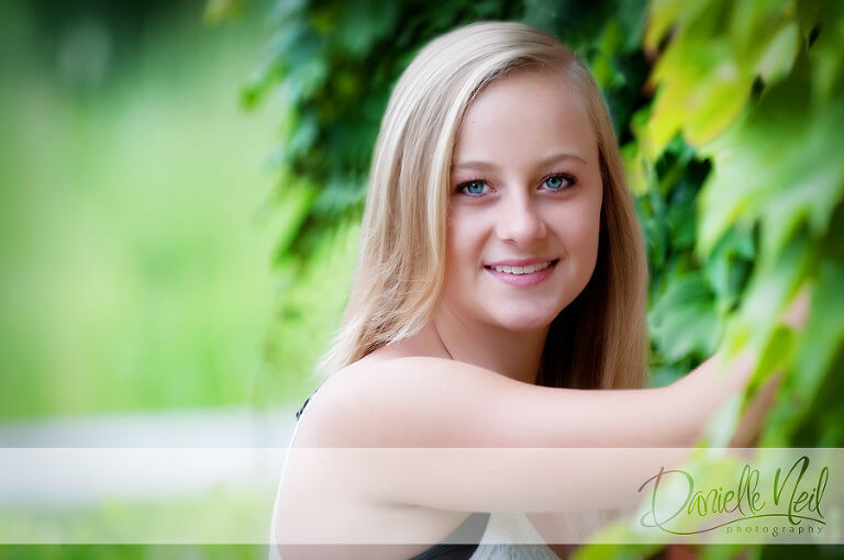 High school senior close-up headshot with a wall of leaves at the park